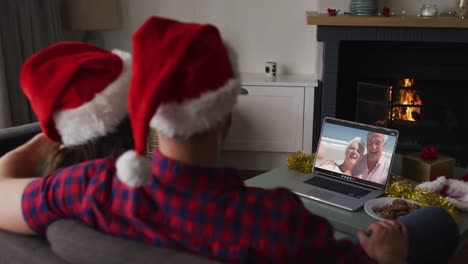 Caucasian-couple-on-video-call-on-laptop-with-grandparents-at-christmas-time