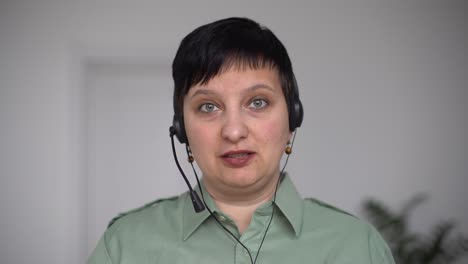mujer con auriculares habla en video chat usando computadora portátil. auto-aislamiento en la pandemia de covid-19. apoyo en línea para mujeres