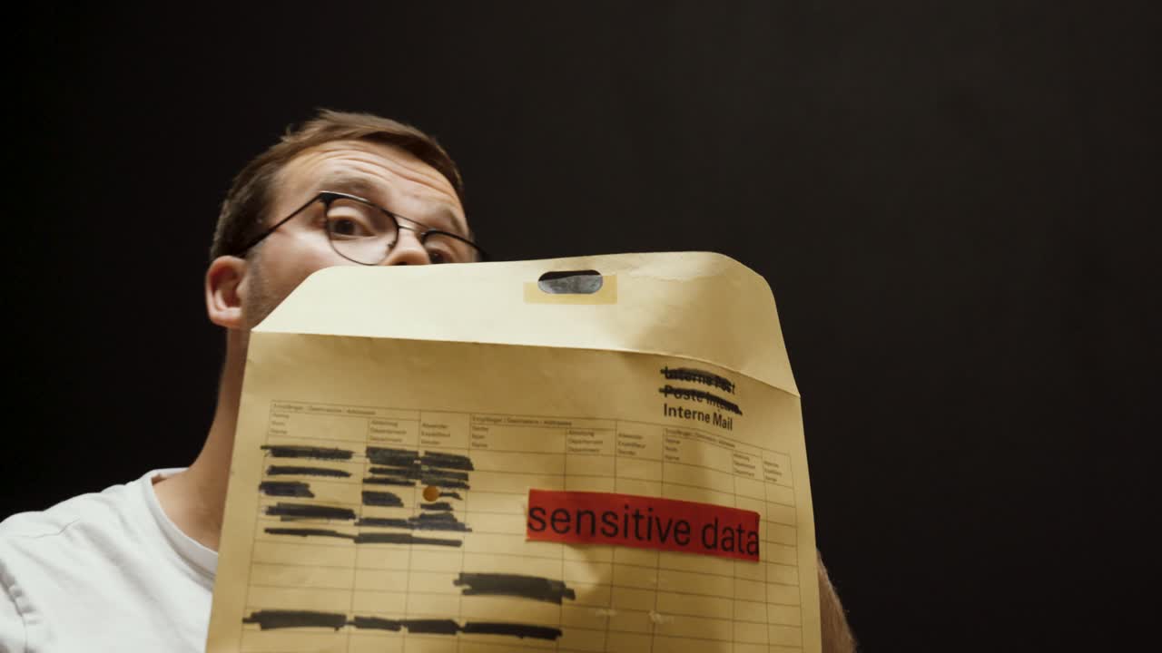 A man secretly opens an envelope labeled "sensitive data" and looks around to check if anyone is watching, symbolizing data theft and espionage risk