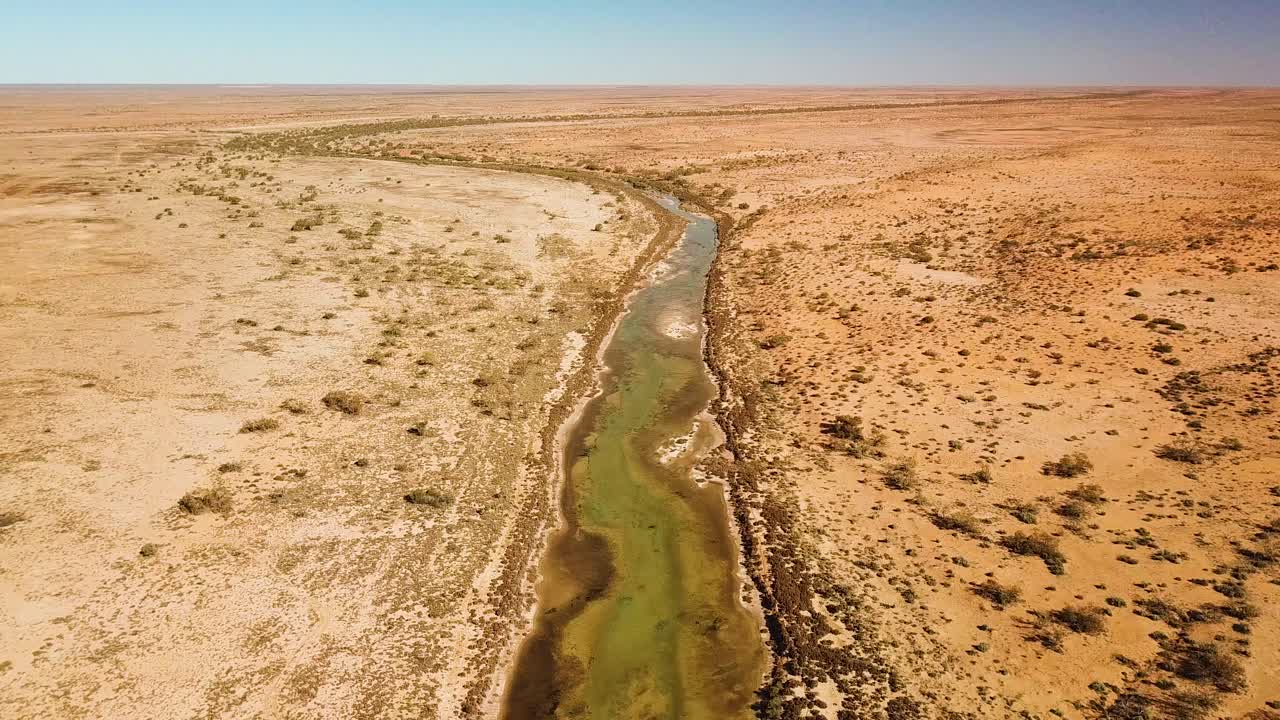 imágenes de drones de alto vuelo de un río alimentado por un manantial que serpentea a través de la árida región del desierto australiano
