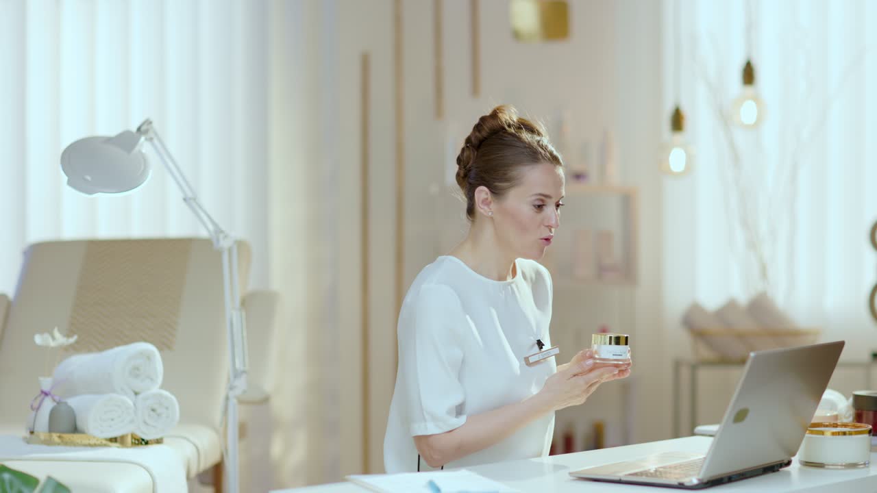 smiling woman employee in beauty studio having video meeting