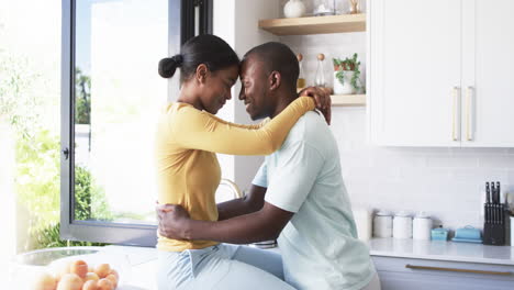 a diverse couple hugs in kitchen, sharing tender moment