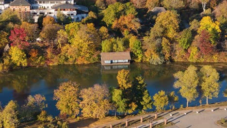 cinematic aerial view of a small house on lake herastrau in bucharest, romania, autumn