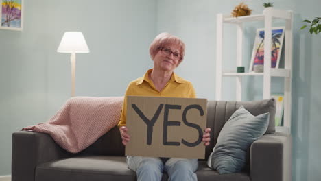 smiling mature lady lifts up sheet with message yes at home