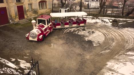 a low level drone shot capturing an empty, fancy looking public tram with a siren, taking a turn in a closed area, in the city of sighisoara on an afternoon