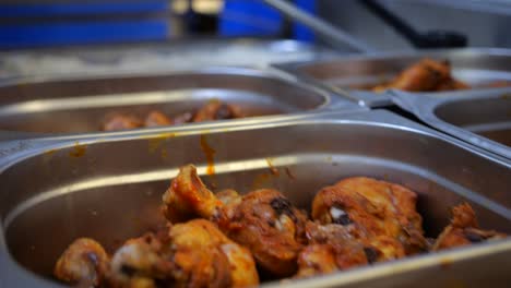 cooked chicken legs on food trolley, prepared restaurant food close up