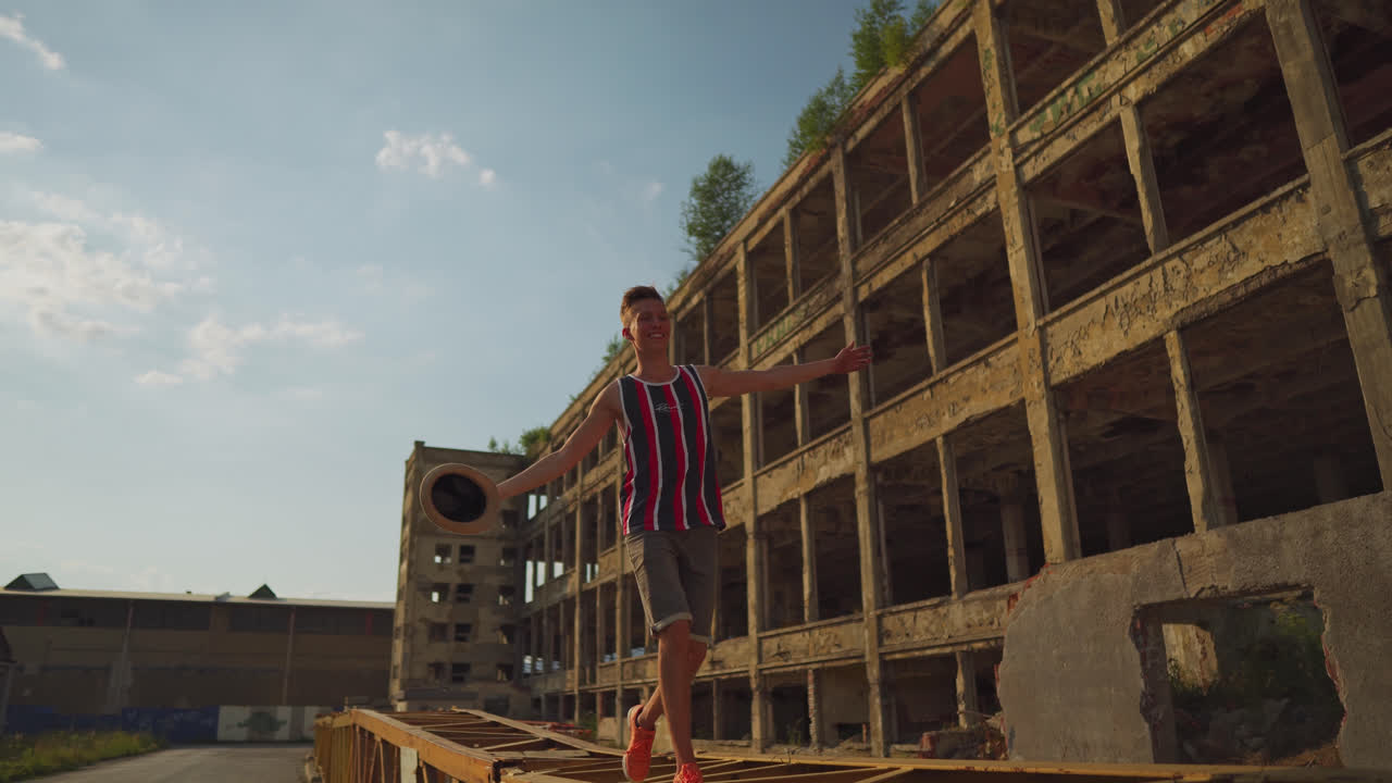 밝고 화창한 날 도시 지역의 금속 바리케이드 위에서 행복하게 달리고 춤을 추는 젊은 남성