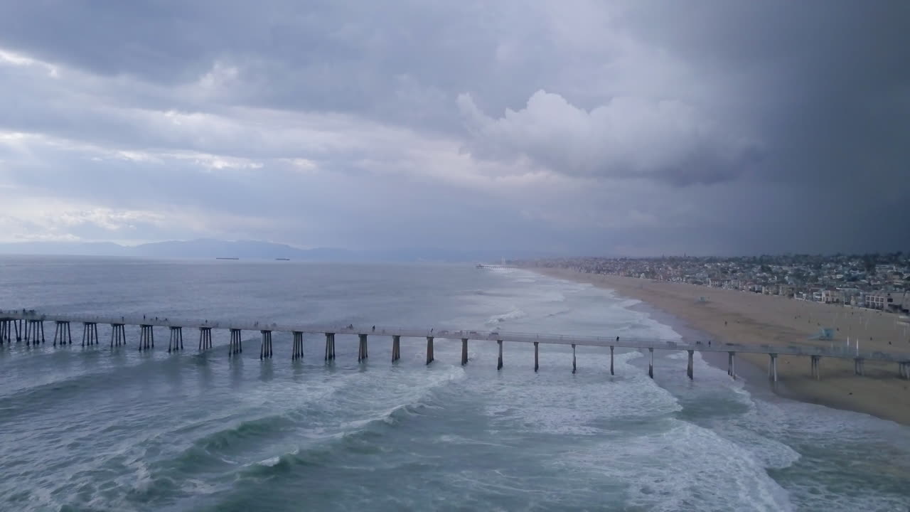 Storm clouds and waves by the Manhattan Beach Pier in California, AERIAL PAN