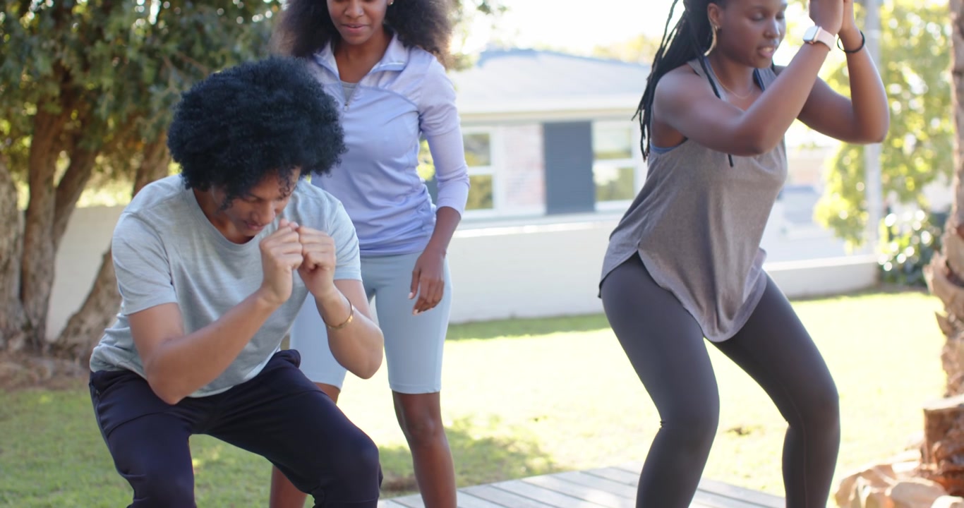 Trio afroamericano accovacciato sul ponte, la donna al centro controlla il ginocchio dell'uomo a sinistra per la postura, con uno smartwatch.