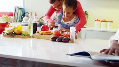 madre ayudando a su hija a cortar verduras en la cocina 4k