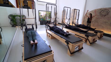 group of women doing exercises on pilates reformers