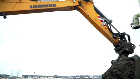 excavator bucket dumping wet cement into a concrete paving machine