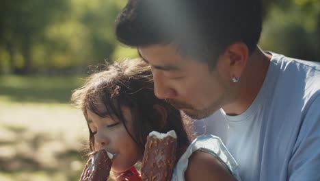 primer plano de feliz padre e hija comiendo helados de chocolate en el parque