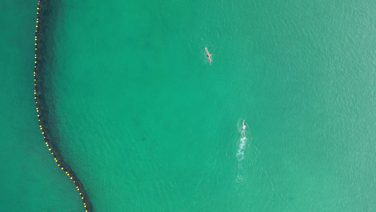 una pareja nadando hacia la otra, estática aérea de arriba hacia abajo