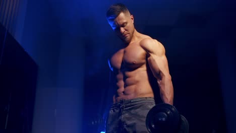 young man holding dumbbell. fit athlete working out biceps at the gym