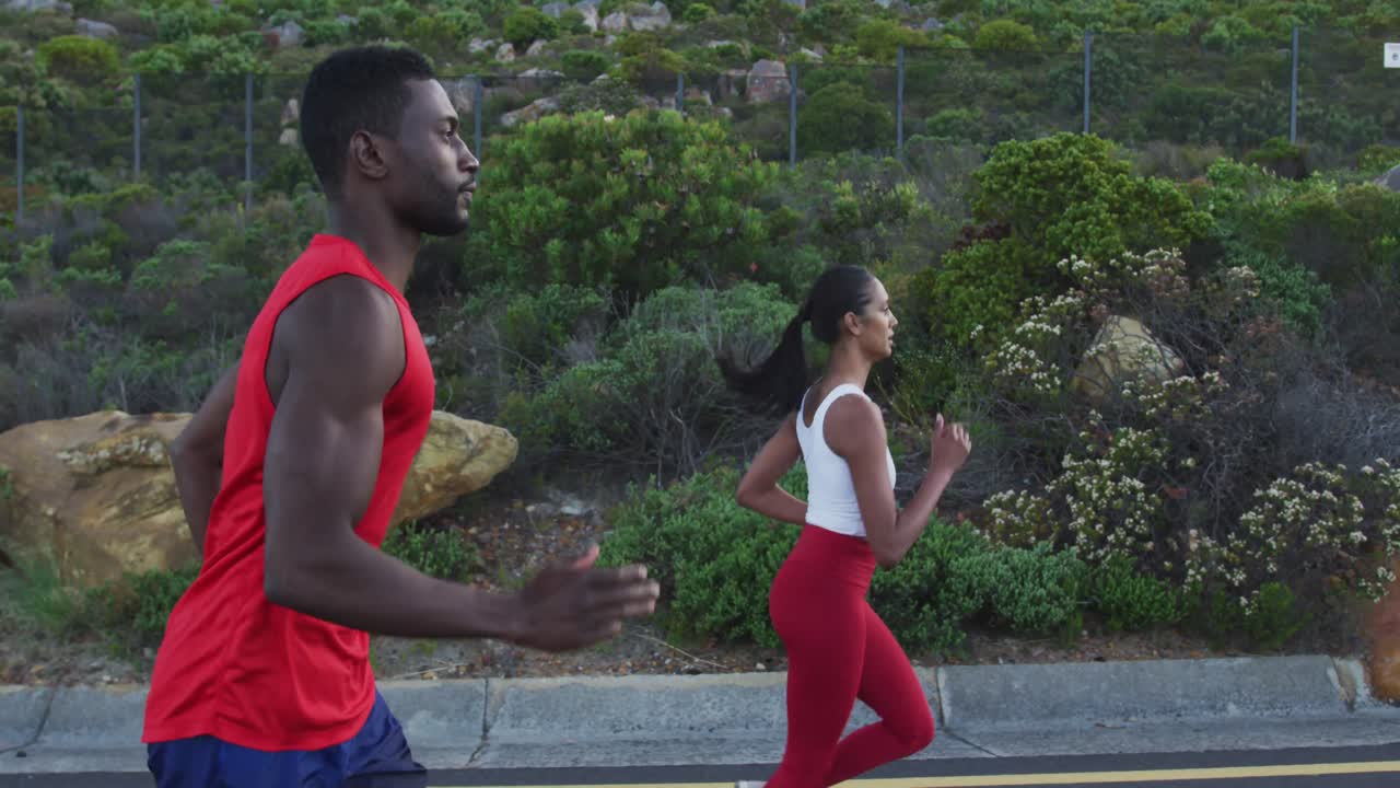 Diverse fit couple exercising running on a country road near mountains