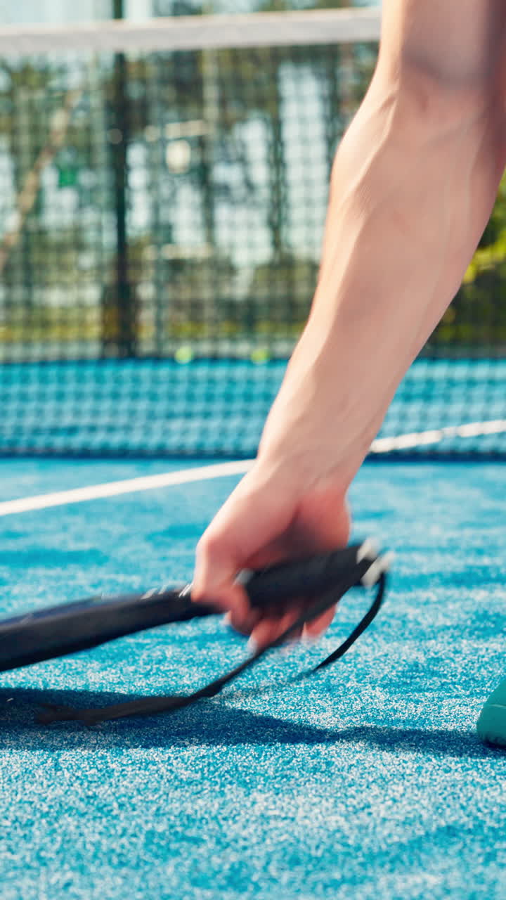 Person som knyter skolissene og server på en padelbane