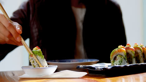 woman having sushi with sauce in restaurant 4k