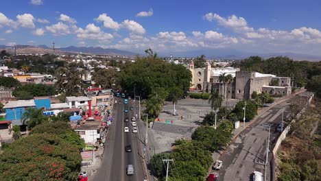 aerial backward view of tlayacapan, morelos, with busy streets, plaza, and historic church of capilla san miguel