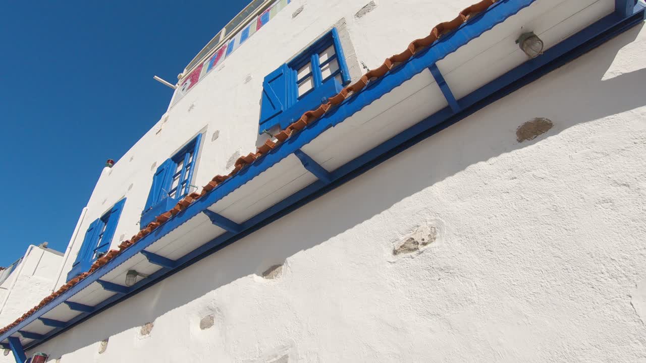 tiro en ángulo bajo del popular edificio de estilo egeo, fachada blanca y marco de ventana azul, ambiente de verano