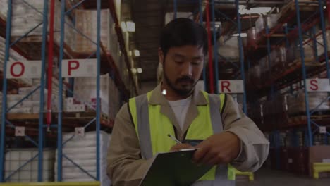 Animation-of-connected-icons-over-portrait-of-smiling-asian-worker-with-checklist-in-warehouse
