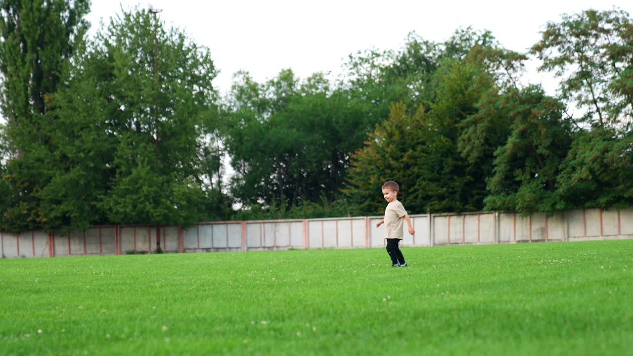 Grandad and grandson play cheerfully on the green lawn. Man follows a baby running by the ball.