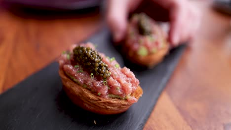 hand placing gourmet food on a slate plate