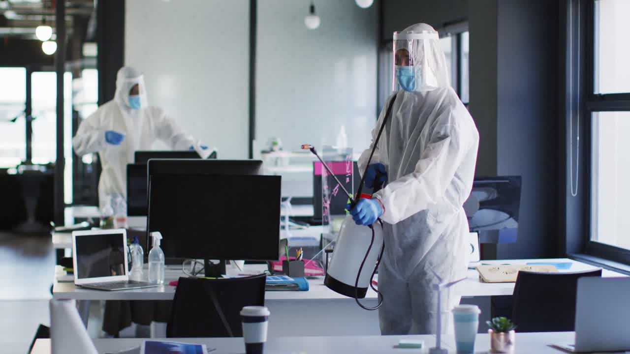 Health worker wearing protective clothes cleaning the office using disinfectant sprayer