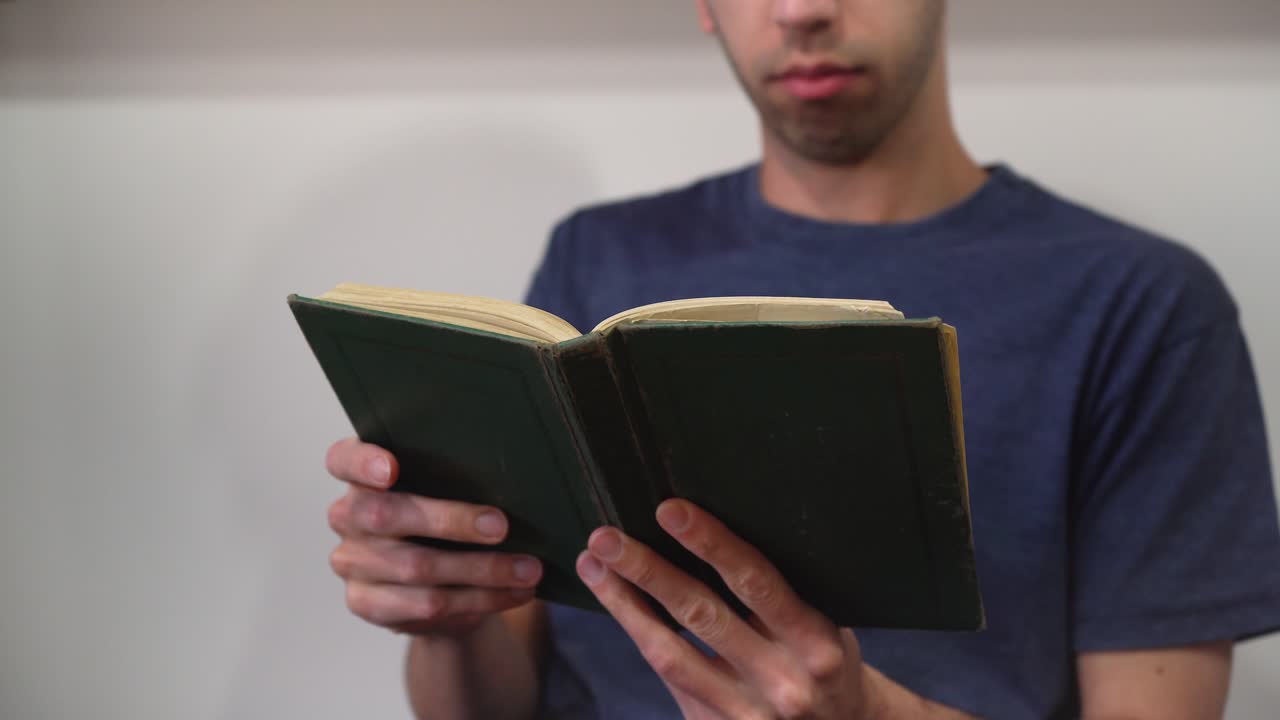 un joven leyendo un libro viejo en su casa