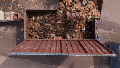 front loader at landfill dumps organic food waste into metal container, aerial