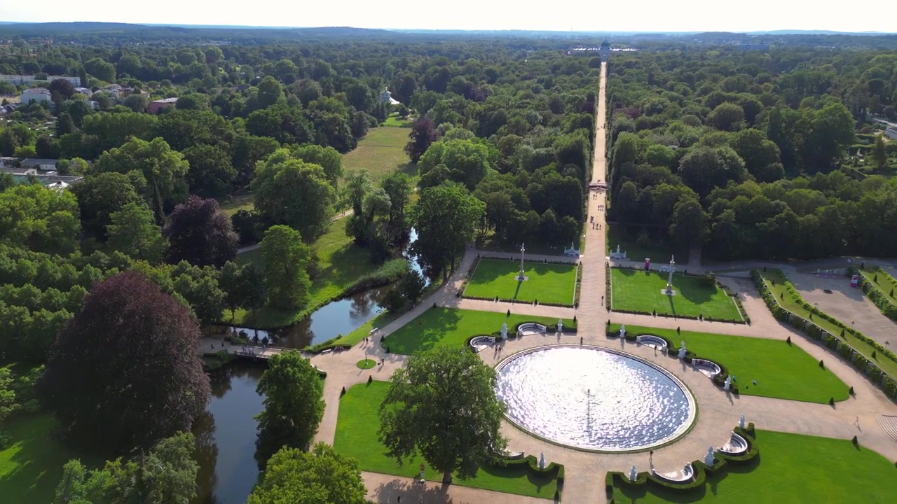 Giornata estiva soleggiata al Palazzo Sanssouci di Potsdam che mostra i bellissimi giardini verdi e l'area circostante. Rotazione fluida del drone con vista aerea verso destra.