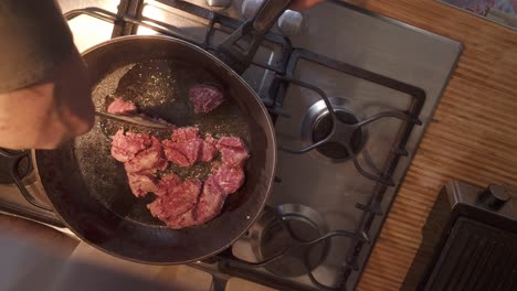 domestic cook stirring mince beef in hot frying pan top down view