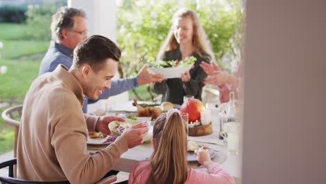 video de padres caucásicos felices, hija y abuelos que sirven comida en una mesa al aire libre
