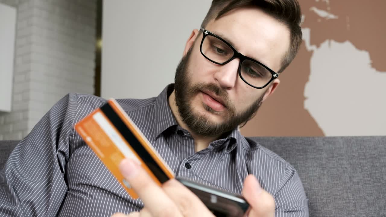 Uomo che acquista online con smartphone e carta di credito/bancaria.