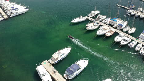 boats docked at a marina with a small motorboat cruising through turquoise waters on a sunny day