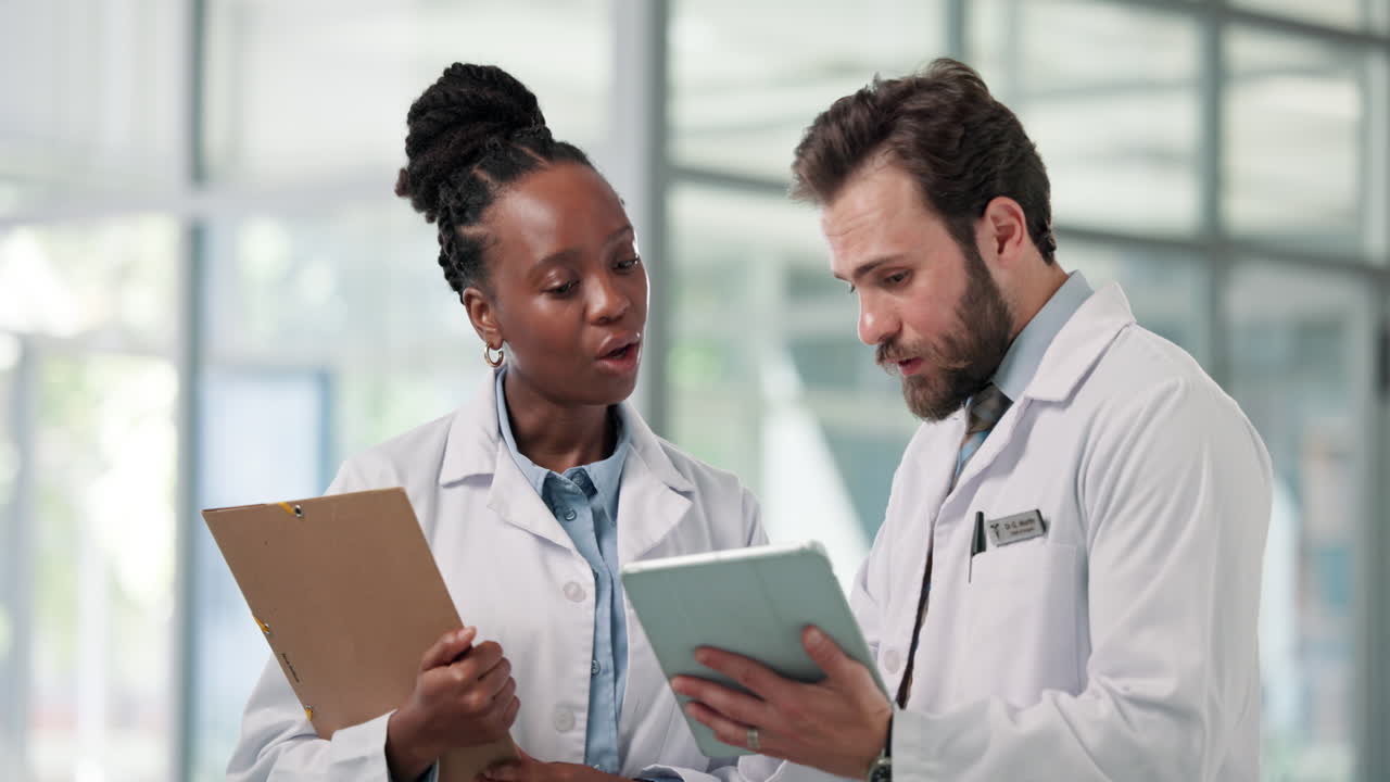 Two Diverse Doctors Discussing Medical Information on a Digital Tablet