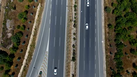 tiro aéreo sobre una intersección de carretera ocupada que lo enrosca a través de campos verdes exuberantes y prados