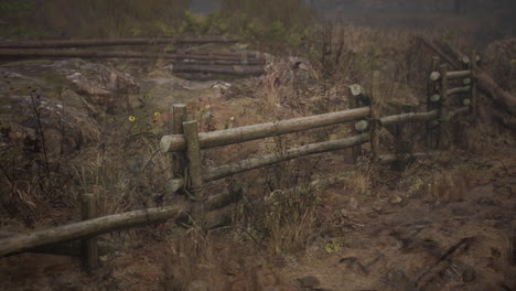 una vieja valla de madera con un campo de campo detrás de ella