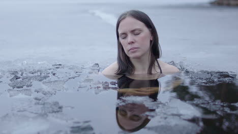 Serene-slider-shot-of-a-beautiful-woman-in-an-ice-cold-lake-at-dusk,-closeup