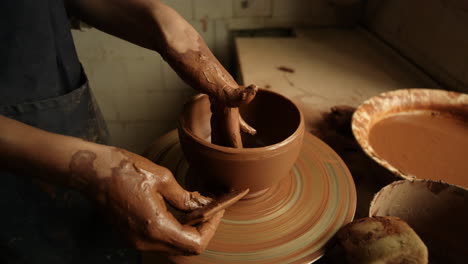 unknown girl working with wet clay in pottery. woman sculpting clay pot