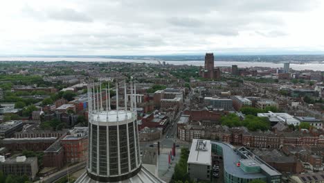aerial view of liverpool metropolitan cathedral and surrounding cityscape, with river mersey and anglican cathedral visible in the distance on a cloudy day