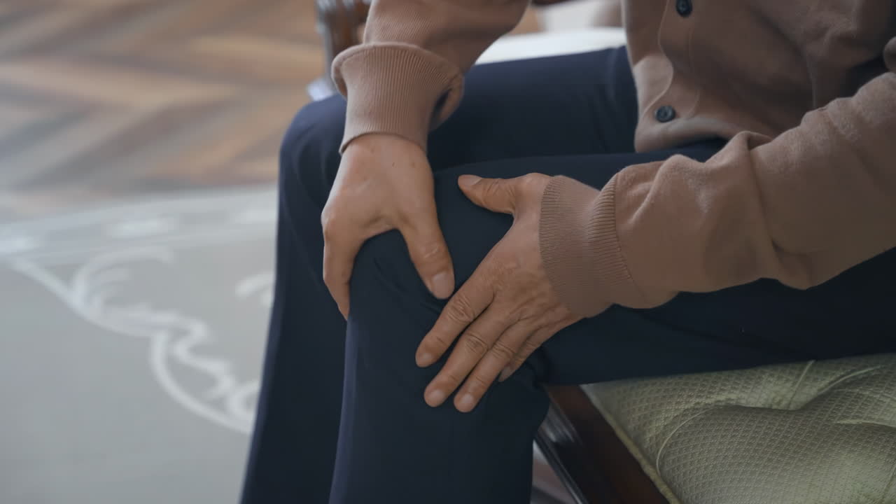 Manos de un hombre mayor maduro (abuelo) sosteniendo una rodilla crónica con expresión de dolor, por artritis reumatoide, osteoporosis y problemas de piernas para el cuidado de la salud. Concepto de aprender a estar solo después de la jubilación.