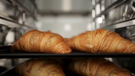 freshly baked croissants on metallic shelves, close-up, elevator shot