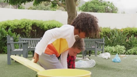 Video-of-two-happy-diverse-schoolboys-collecting-rubbish-for-recycling-in-schoolyard