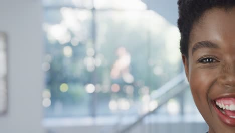 retrato de video de la mitad de la cara de una doctora afroamericana sonriente en el hospital, con espacio para copiar