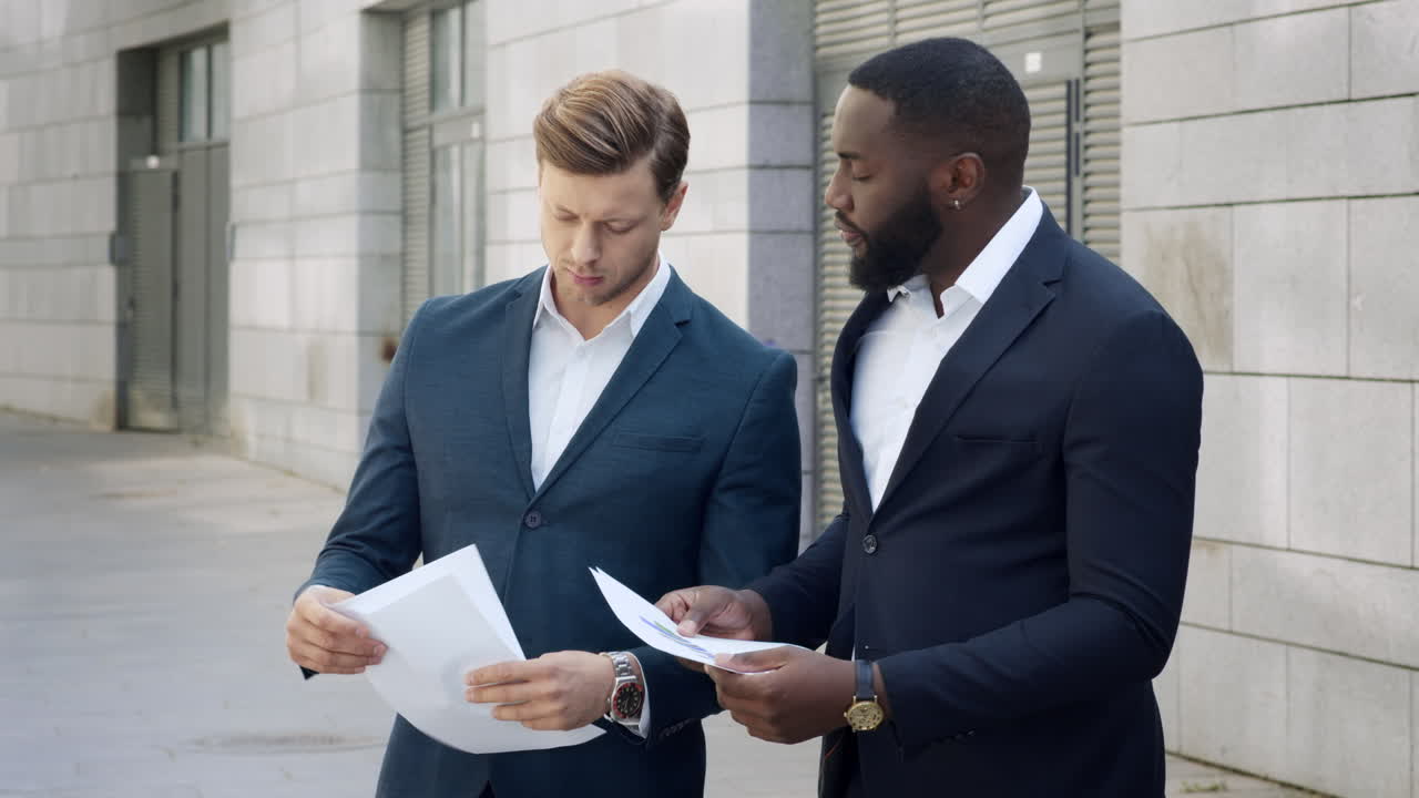 Businessmen discussing documents on street.Employees standing on street together