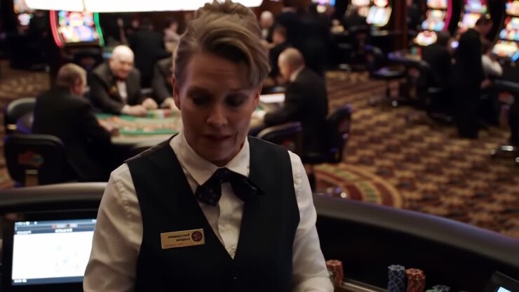 Un dipendente professionista di un casinò impegnato nelle sue mansioni, che supervisiona i giochi di carte e le slot machine mantenendo un'atmosfera accogliente per giocatori d'azzardo e visitatori in un ambiente di casinò affollato