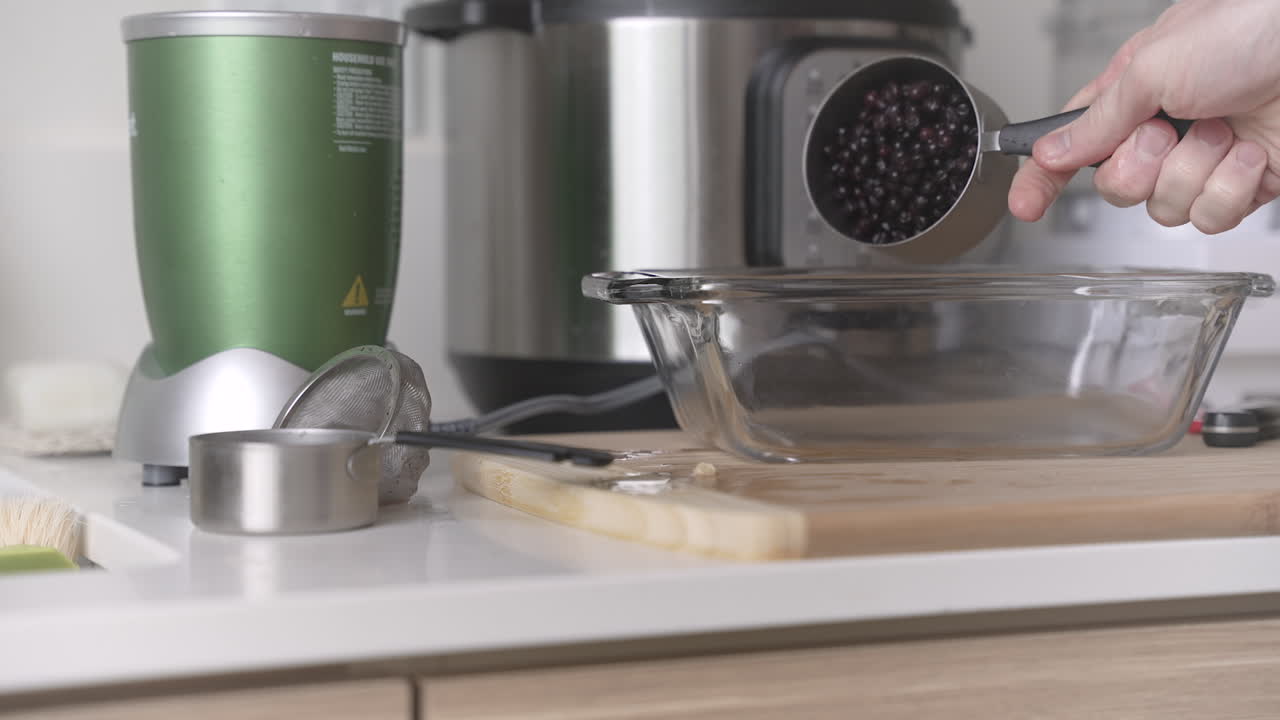 Pouring blueberry base into loaf baking pan on a modern countertop, creating a vegan breakfast cake