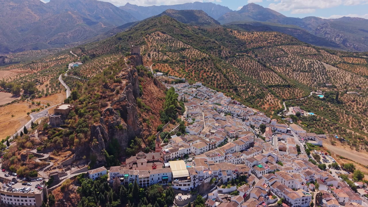Luftfoto langs ryggen af Zahara de la Sierra med olivenlunde, der dækker skråningerne, Spanien