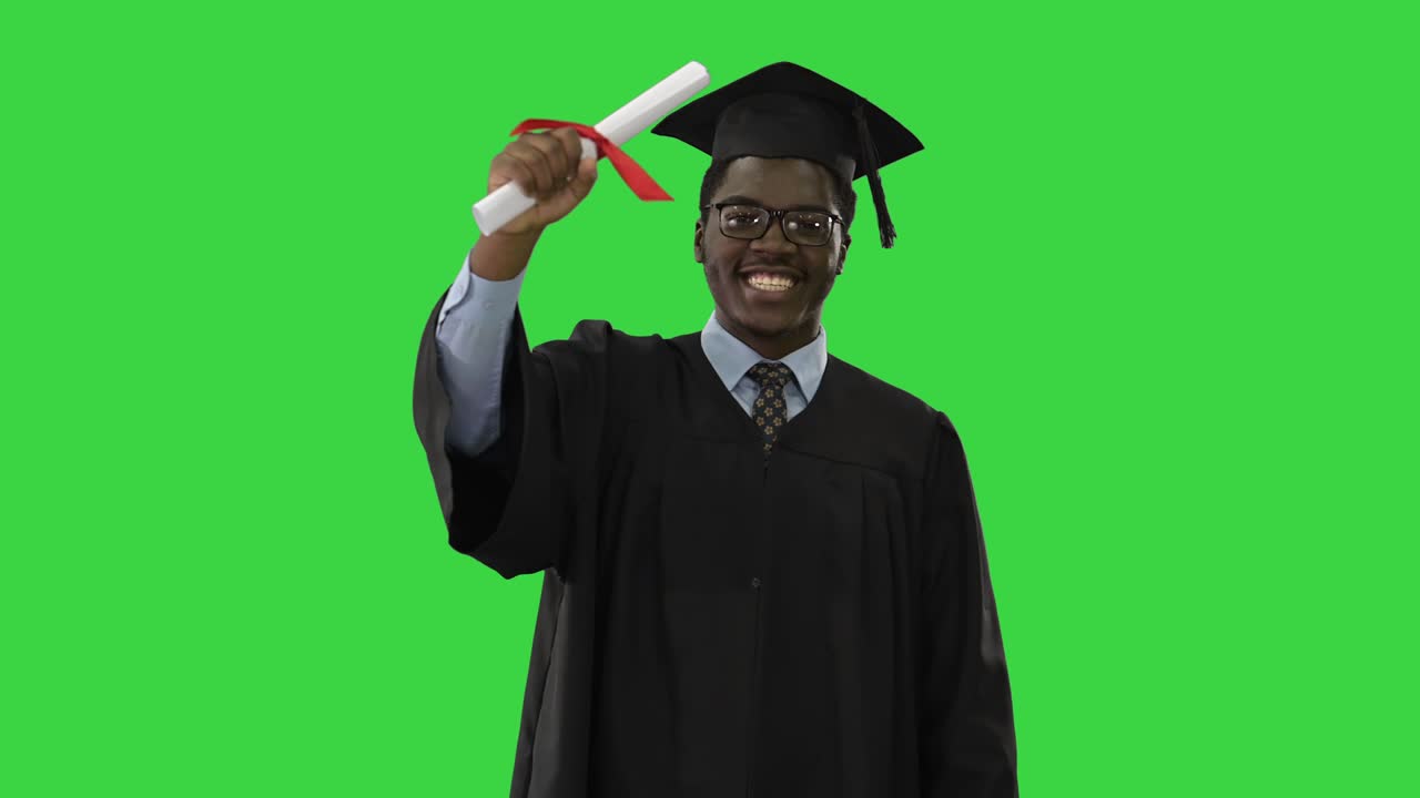 Happy african american male student in graduation robe walking towards camera waving his diploma on a Green Screen, Chroma Key
